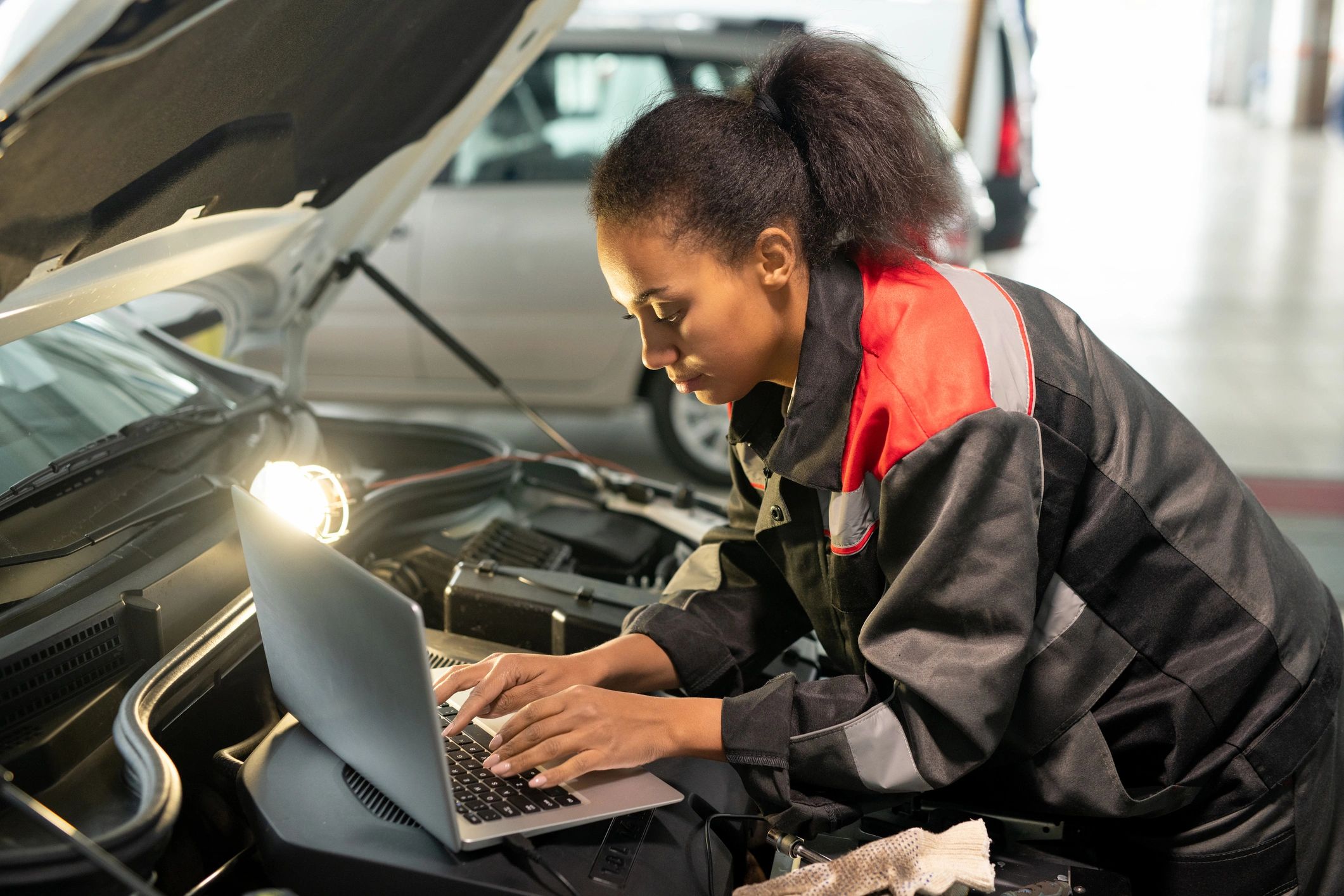 Service advisor using a laptop over an open engine bay to look up parts information