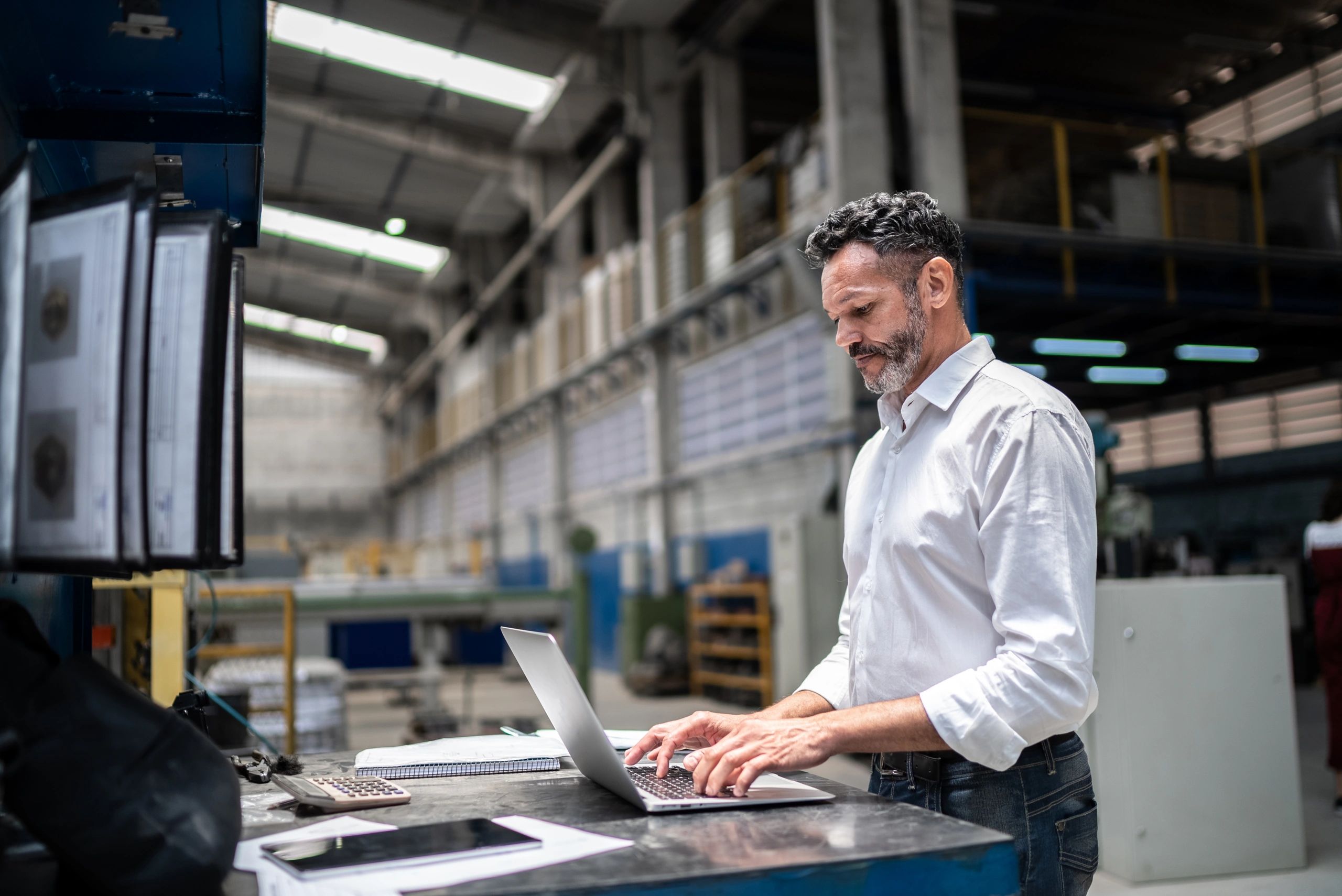 Business professional using a laptop in an industrial setting
