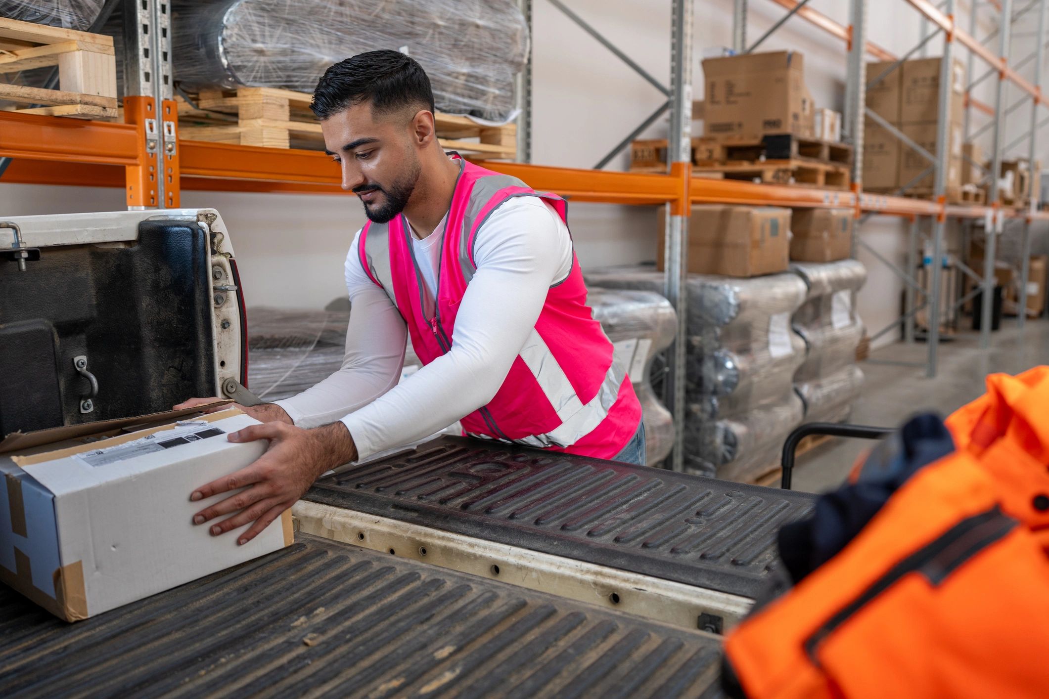 Logistics worker loading packaged boxes into a delivery vehicle at a warehouse